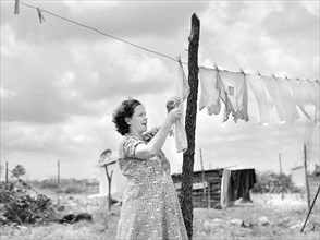 Mrs. Agnes Usher hanging Clothes at her new prefabricated house at Hazlehurst Farms Inc.