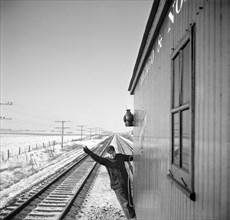 Brakeman giving OK signal from Caboose during Freight Train Operations on Chicago and North Western Railroad between Chicago