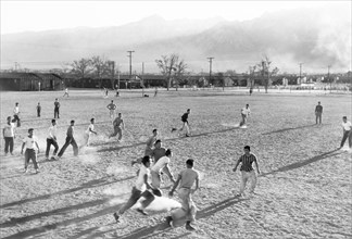 Boys playing Football on dusty Field