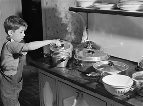 Young Boy checking Pots of Food on Stove for Thanksgiving Dinner
