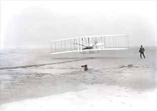 Wilbur Wright lying on machine
