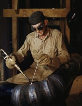 Welder gas welding a joint in a line of spiral pipe