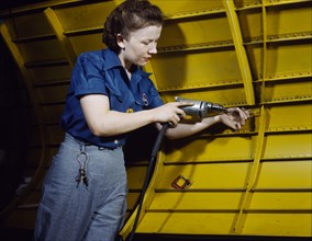 Woman operating hand drill on "Vengeance" dive bomber