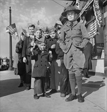 Boy Scout leading group of Young boys wearing garrison caps and holding American Flags at start of Parade and Flag Dedication Ceremony at Office of Civil Defense Headquarters