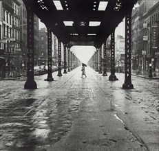 Woman with umbrella walking across Third Avenue at East 41st Street under partially dismantled Elevated Railway Tracks
