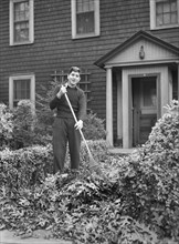 Man raking leaves in front yard of his house