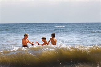 Three Boys playing in Ocean at Beach