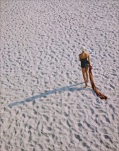 Rear View Portrait of Woman in One-Piece Swimsuit walking on Beach