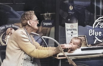 Elderly Woman feeding Baby in Baby Carriage