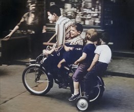 Four Children riding Bicycle on Sidewalk
