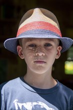 Head and shoulders portrait of young boy wearing straw hat