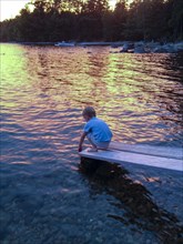 Young boy at end of lake boat ramp at sunset