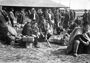Prisoners resting on their luggage while awaiting order to move to repatriation points