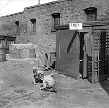 Two children playing marbles outside public toilet
