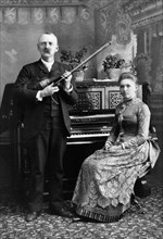 Portrait of Man holding Violin and Woman seated at Piano