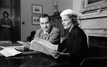 U.S. Vice President Richard Nixon with his wife Pat Nixon looking at documents  in his office