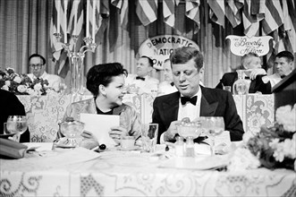 Actress Judy Garland seated next to U.S. Senator John F. Kennedy at dinner