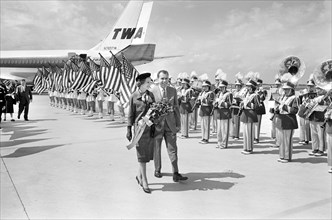 U.S. Vice President Richard M. Nixon with his wife Pat Nixon walk by  band and American flags at airport during campaign trip