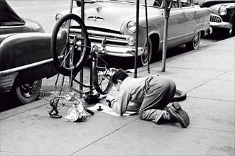 Man fixing bicycle on sidewalk