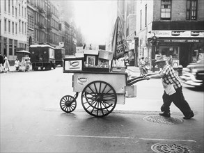 Man pushing hot dog cart across street