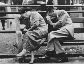 Woman and man napping on park bench