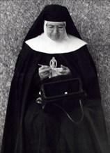 Nun sitting and knitting with purse open on lap