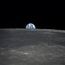 View from Apollo 11 spacecraft of moon with Earth on horizon