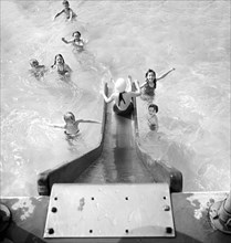High angle view  of children entering swimming pool from water slide, Greenbelt, Maryland, USA,