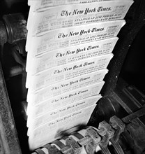 New York Times finished papers coming out of cutting and folding machines on rapidly moving belt,