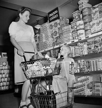 Woman and young boy shopping in cooperative grocery store in federal housing project, Greenbelt,