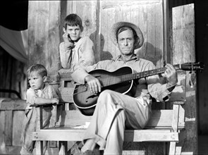 Father playing acoustic guitar with two sons, Natchitoches, Louisiana, USA, Marion Post Wolcott, U