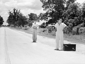 Two young men waiting for a ride on rural road, Natchitoches, Louisiana, USA, Marion Post Wolcott,