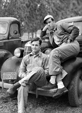 Two construction workers from Monroe, Louisiana sitting on car in front of their shacks before