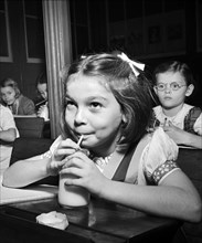 Young girl drinking glass of milk in classroom, New York City, New York, USA, Marjory Collins, U.S.