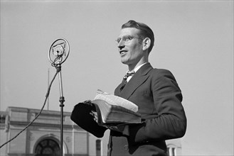 Itinerant preacher broadcasting to his audience by means of public address system on street,