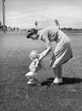Farm worker's wife teaching her baby girl to walk, FSA (Farm Security Administration) labor camp,