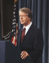 U.S. President Jimmy Carter at podium during news conference, half-length profile portrait,