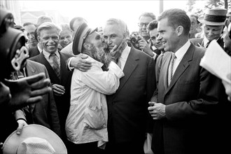 U.S. Vice President Richard Nixon watching as man kisses Soviet politician Frol Kozlov during