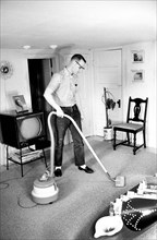 Charles Cline, married student at University of Illinois, vacuuming his apartment, Champaign,