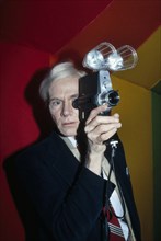 American pop artist Andy Warhol, half-length portrait looking through lens of Polaroid Polavision