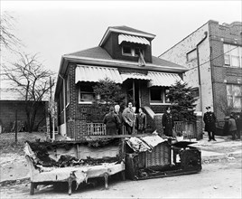 Exterior view of the home of Malcolm X after it was firebombed, remains of charred furniture in