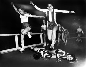 Two women's league roller derby skaters leap over two who have fallen, Al Aumuller, New York