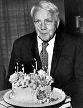 American poet Robert Frost, half-length portrait with his birthday cake on his 85th birthday,