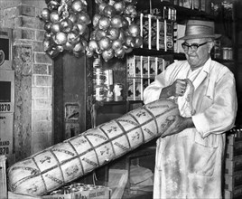 Anthony Nocella lifting a 110-pound provolone cheese at G. Nardella & Sons specialty shop, Brooklyn