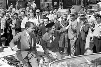 U.S. Vice President Richard Nixon with his wife Pat Nixon wave to crowds while riding in open car