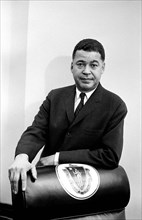 Senator Edward Brooke standing behind chair decorated with Great Seal of the Commonwealth of