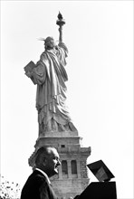 U.S. President Lyndon B. Johnson speaking at podium with Statue of Liberty in background before