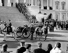 Flag-draped casket of late U.S. President John Kennedy carried by horse-drawn caisson, arriving at