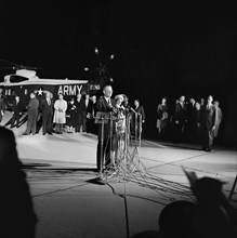 U.S. President Lyndon B. Johnson (at microphones), standing beside First Lady Claudia 'Lady Bird'