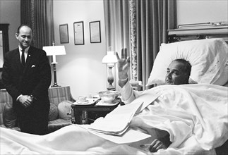 Paul Glynn looking on as U.S. President Lyndon Johnson giving OK sign from his hospital bed